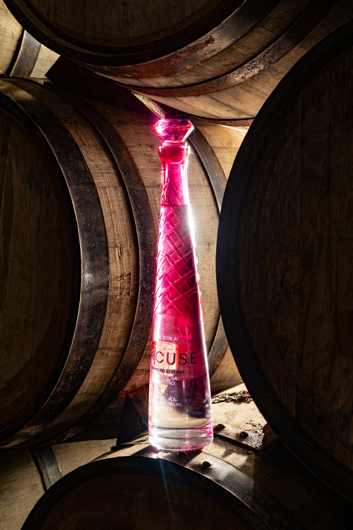 Excuse Tequila Diamond Top Edition bottle among oak casks in the distillery